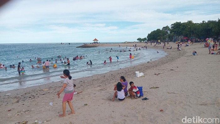 Keramaian wisatawan yang sedang bersantai atau berenang di Pantai Bangsal Sanur, Rabu (23/4/2025).