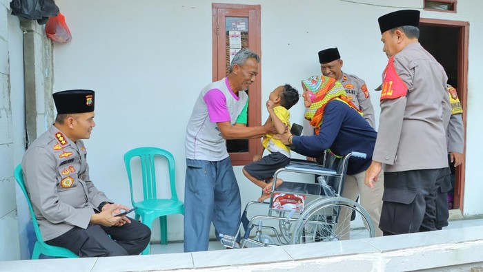Polres Metro Bekasi menyerahkan bantuan kursi roda kepada warga.