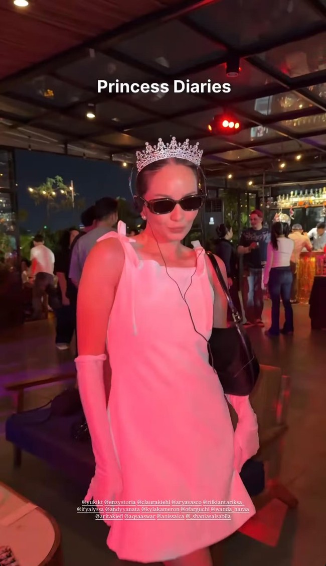 Enzy Storia tampil cantik bergaya seperti Princess Mia di film Princess Diaries. Dress mini putih dipadukan dengan sarung tangan senada dan kaca mata hitam. Tak lupa untuk melengkapinya Enzy juga memakai mahkota di atas kepalanya dan headphone kabelnya. Foto: Instagram