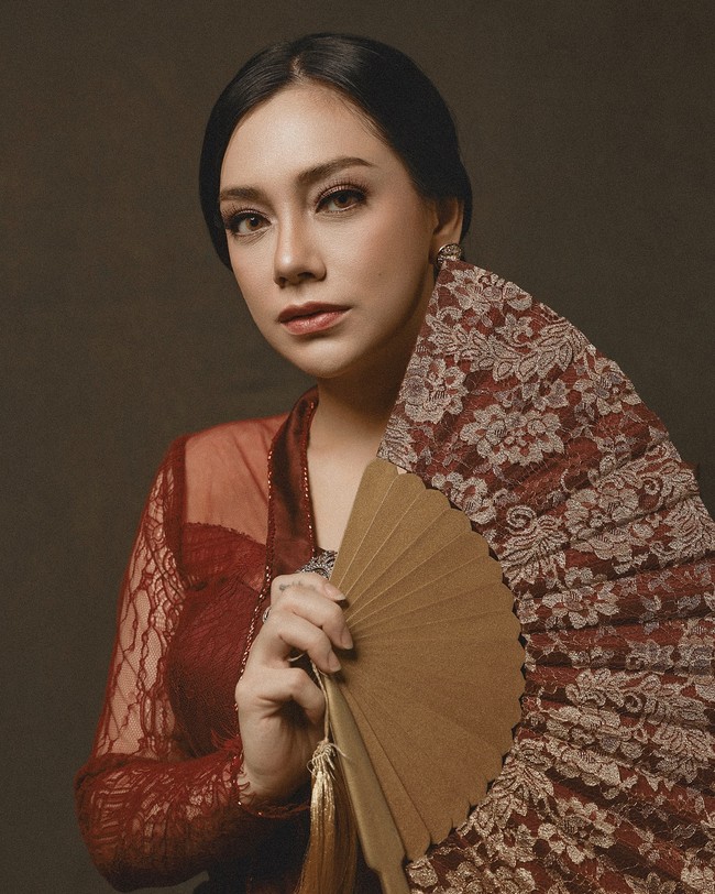 Berpose memegang kipas, wajah wanita kelahiran 2 April 1992 itu tampil flawless berkat sentuhan makeup dari Donnyndut Wedding Makeup. Tatanan rambutnya sengaja disanggul sehingga membuatnya terlihat elegan. Foto: Dok. Instagram @celine_evangelista.