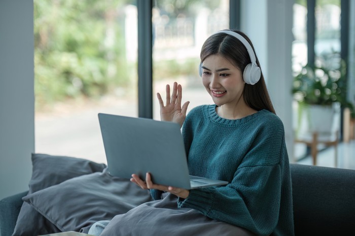 Work at home young asian woman working on laptop computer while sitting and hold coffee cup at home Morning lifestyle concept