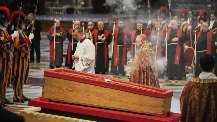 Cardinal Camerlengo Kevin Joseph Farrell, center right, spreads incense around the body of Pope Francis inside St. Peters Basilica at the Vatican, Wednesday, April 23, 2025, where he will lie in state for three days. (AP Photo/Alessandra Tarantino)
