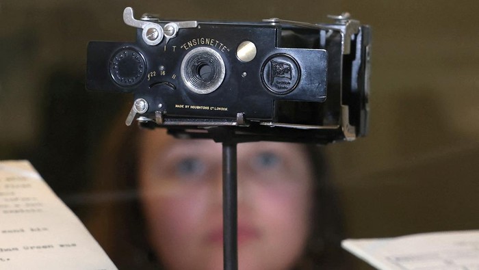 An employee poses as she views a D-Day landings decoy routes map and photographs of suspected spies which form part of ‘MI5: Official Secrets’, a new exhibition exploring the history of the British intelligence agency, at The National Archives in London, Britain, April 1, 2025. REUTERS/Toby Melville     TPX IMAGES OF THE DAY