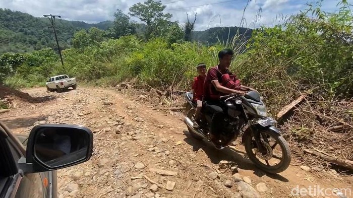 Salah satu warga di Kabupaten Paluta saat melintas di jalan rusak (Nizar Aldi/detikSumut)