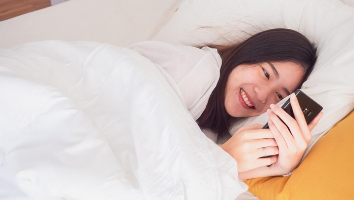 asian girl wake up on bed and playing with the mobile phone