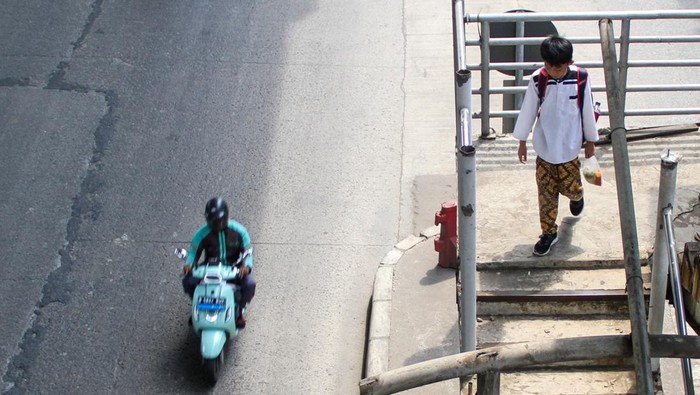Pejalan kaki berjalan di jembatan penyeberangan orang (JPO) yang bagian kiri dan kanan pagar pelidungnya telah hilang dicuri di Jalan Raya Bekasi, Cakung Jakarta, Jumat (25/4/2025). Kondisi jembatan penyeberangan tersebut  membahayakan bagi pengguna JPO itu. ANTARA FOTO/Fathul Habib Sholeh/Spt.