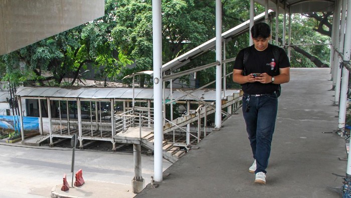 Pejalan kaki berjalan di jembatan penyeberangan orang (JPO) yang bagian kiri dan kanan pagar pelidungnya telah hilang dicuri di Jalan Raya Bekasi, Cakung Jakarta, Jumat (25/4/2025). Kondisi jembatan penyeberangan tersebut  membahayakan bagi pengguna JPO itu. ANTARA FOTO/Fathul Habib Sholeh/Spt.