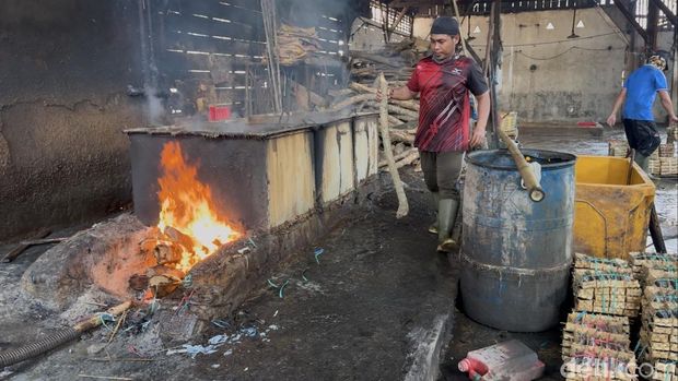 Pekerja memasukkan kayu bakar di rumah produksi pindang, Rembang, Sabtu (26/4/2025).