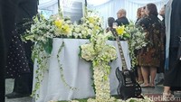 Bunga putih dan gitar hitam di depan peti jenazah Ricky Siahaan. Foto: Febri/detikcom