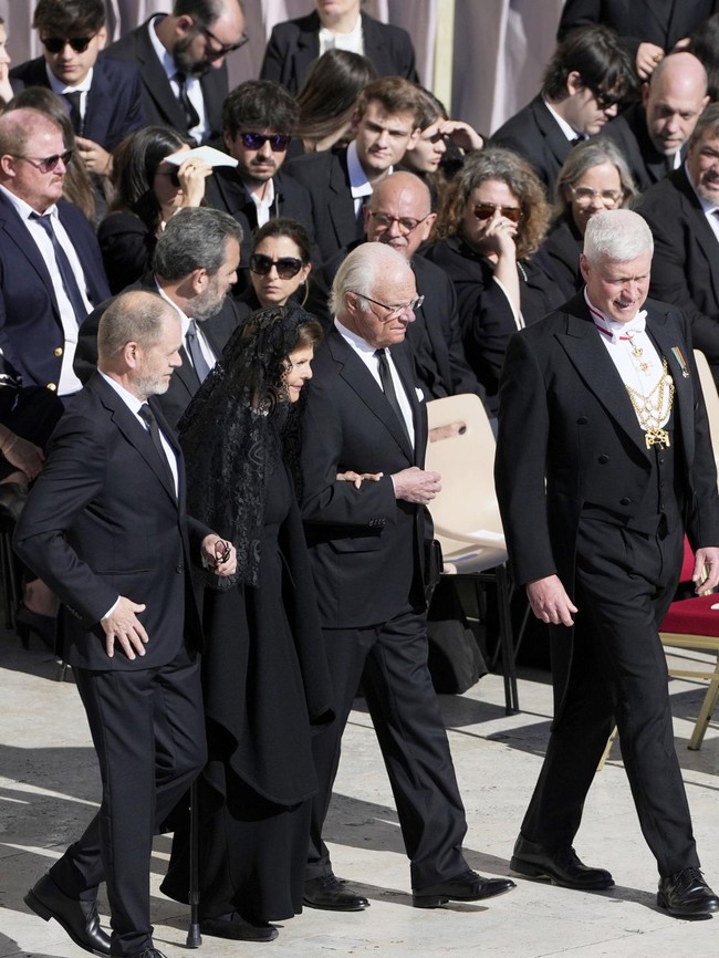 Raja Swedia Carl XVI dan Ratu Silvia pun turut hadir di pemakaman yang berlangsung di Lapangan Santo Petrus, Vatikan. Ratu Silvia tampil berbalut gaun hitam panjang. Veil lace melengkapi penampilannya. Foto: AP/Markus Schreiber
