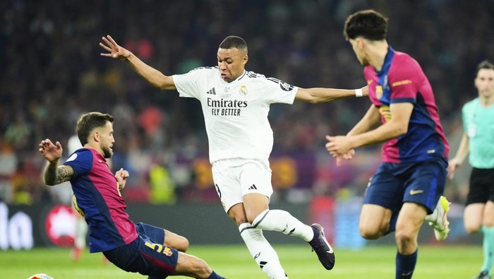 Real Madrids Kylian Mbappe, centre, challenges for the ball with Barcelonas Inigo Martinez, left, during the Spanish Copa del Rey final soccer match between Barcelona and Real Madrid at Estadio de La Cartuja stadium in Seville, Spain, Saturday, April 26, 2025. (AP Photo/Jose Breton)