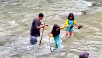 Seorang siswi nyaris terpeleset saat berusaha melintasi sungai. Pegangan tangan dan tongkat kayu menjadi tumpuan agar tidak terseret arus.