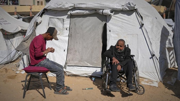 Ribuan Pasien Cuci Darah Gaza Berjuang di Tengah Perang Wasem Attiya pushes his father, Mohamed, 54, in a wheelchair as they head to Shifa hospital in Gaza City for a dialysis session, Monday, April 14, 2025. (AP Photo/Jehad Alshrafi)