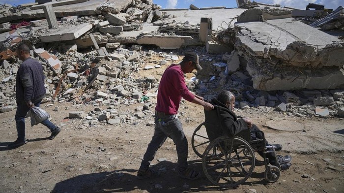 Wasem Attiya pushes his father, Mohamed, 54, in a wheelchair as they head to Shifa hospital in Gaza City for a dialysis session, Monday, April 14, 2025. (AP Photo/Jehad Alshrafi)