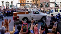 Orang-orang bereaksi saat mobil jenazah yang membawa peti jenazah Paus Fransiskus melewati Corso Vittorio pada hari pemakamannya, di Roma, Italia. REUTERS/Matteo Ciambelli