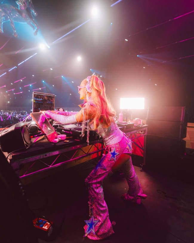 Wanita 44 tahun ini tampil dengan tatanan rambut half-ponytail. Bagian atas rambutnya diikat tinggi, sementara sisanya dibiarkan tergerai. Volume ponytail-nya tebal dan bouncy, memberikan kesan playful dan meriah khas festival. Foto: Instagram/@parishilton