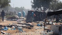 Para migran berdiri di dekat tenda-tenda yang terbakar, saat otoritas Tunisia membongkar kamp-kamp sementara yang menampung para migran Afrika sub-Sahara, di Amra, Sfax, Tunisia, Jumat (25/4/2025).  