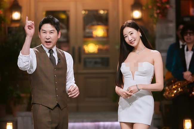 Dalam segmen bersama presenter Shin Dong Yup, Kim Sa Rang memakai mini dress putih dengan belahan dada rendah. Ia terlihat cantik dengan rambut panjang terurai dan wajah yang flawless. Foto: Instagram @sarangkim.love