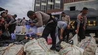 Anggota kepolisian mengumpulkan minuman keras untuk dimusnakan saat Pemusnahan Barang Bukti Minuman Keras Beralkohol di Halaman Polres Ternate, Maluku Utara, Selasa (29/4/2025).
