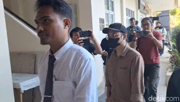 Dokter YA (bertopi dan bermasker) saat memenuhi panggilan pemeriksaan di Polresta Malang Kota.