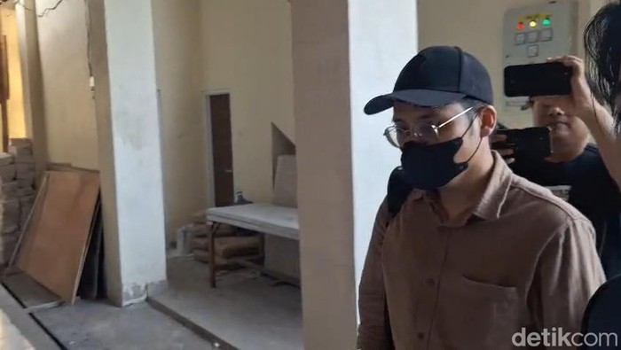 Dokter YA (bertopi dan bermasker) saat memenuhi panggilan pemeriksaan di Polresta Malang Kota.