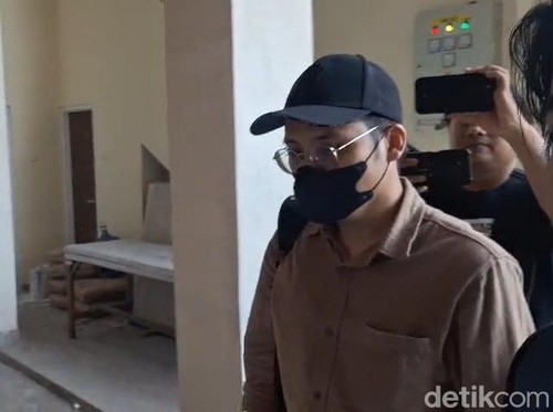 Dokter YA (bertopi dan bermasker) saat memenuhi panggilan pemeriksaan di Polresta Malang Kota.