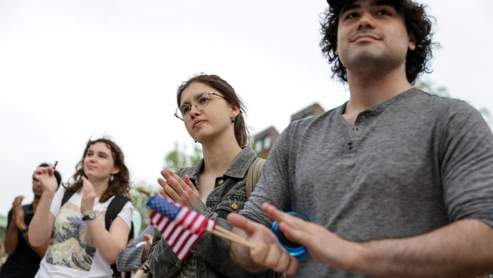 A demonstrator holds a U.S. flag across their chest at a 