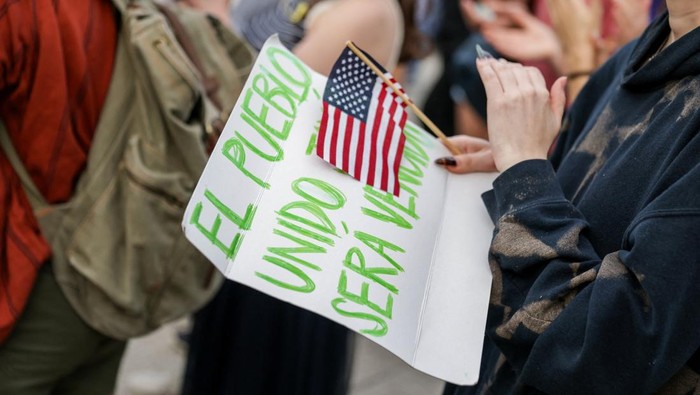 Mahasiswa Harvard Serukan Solidaritas dalam Aksi Damai A demonstrator holds a U.S. flag across their chest at a