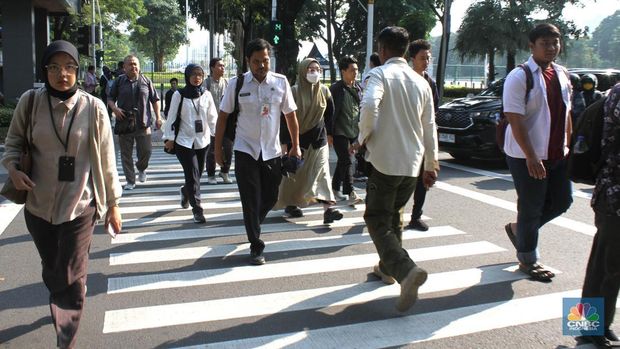 Sejumlah Aparatur Sipil Negara (ASN) berjalan usai naik transportasi umum di kawasan Balai Kota, Jakarta Pusat, pada Rabu (30/4/2025). (CNBC Indonesia/Muhammad Sabki)