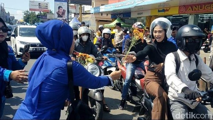 Buruh di Gowa membagikan bunga ke pengendara saat peringatan Hari Buruh.