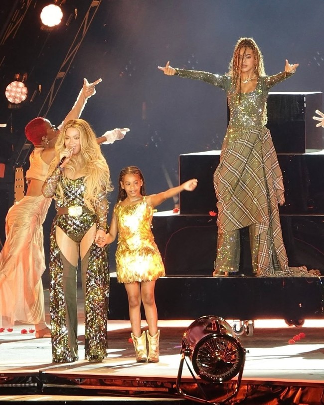 Para penonton konser perdana Cowboy Carter mendapat kejutan istimewa dengan kehadiran Rumi Carter, satu dari kembar bungsu anak Beyonce dan Jay Z. Rumi tampil di panggung dengan mini-dress emas rancangan Oscar de la Renta. Sementara itu, Beyonce dan Blue Ivy, yang termasuk dalam tim penari, kompak berbalut kostum dari Burberry. (Foto: Instagram/@vogue)