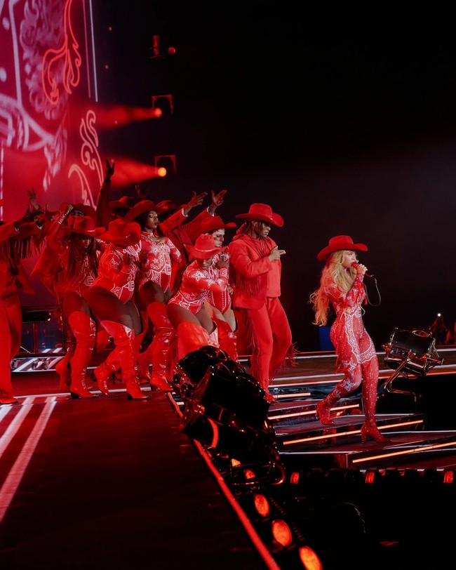 Dalam salah satu segmen paling playful, Beyoncé tampil mengenakan catsuit bermotif kemeja koboi dengan print bandana merah-putih, rancangan Moschino. Motif bandana ini adalah simbol ikonis dalam budaya koboi dan musik country, tapi rumah mode Italia itu mengemasnya ulang dalam gaya khas mereka yang teatrikal, ironis, dan sangat fashion-forward. (Foto: Instagram/@beyonce)
