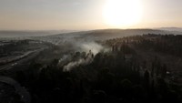 Asap pekat terlihat membumbung di kawasan Latrun, Israel tengah, saat kebakaran hutan melanda akibat suhu ekstrem dan angin kencang, Jumat (2/5/2025).