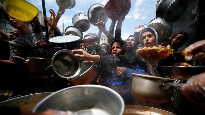 Palestinians wait to receive food cooked by a charity kitchen, in Beit Lahiya, northern Gaza Strip, April 28, 2025. REUTERS/Mahmoud Issa     TPX IMAGES OF THE DAY