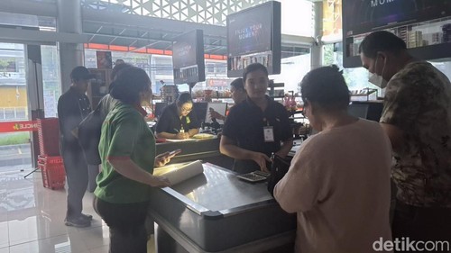 Kasir salah satu supermarket di Denpasar melayani pelanggan dalam kondisi listrik padam, Jumat (2/5/2025).