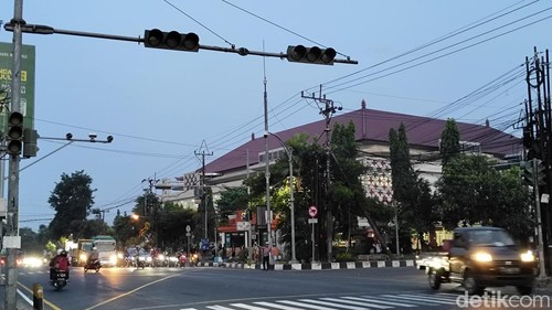 Polisi dari kejauhan tampak berjaga di Simpang Mangupura, Jalur Denpasar-Gilimanuk, Badung untuk mengatur lalulintas manual akibat traffic light mati, Jumat sore (3/5/2025).