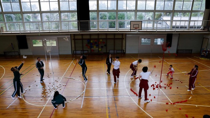 Tourists from abroad wearing school uniforms listen to a woman playing a teacher at a class room while taking part in a Japanese high school experience in Kimitsu, Chiba prefecture, Japan April 23, 2025.  REUTERS/Manami Yamada
