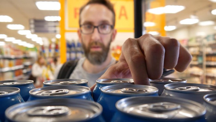 Man shopping in a supermarket while on a budget. He is looking for low prices due to inflation. He is living in the North East of England.