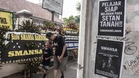 Warga melintas di dekat karangan bunga dukungan untuk SMA Negeri 1 (SMANSA) Bandung saat aksi simpatik di depan gedung sekolah SMA Negeri 1 Bandung, Jawa Barat, Minggu (4/5/2025).
