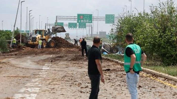Members of Israeli security services inspect a crater near a road outside Israels Ben Gurion airport after a missile launched from Yemen struck the area on May 4, 2025. A missile launched from Yemen struck near Israels main international airport on May 4, Israeli authorities said, an attack that briefly halted air traffic and triggered threats of retaliation. (Photo by Jack GUEZ / AFP)