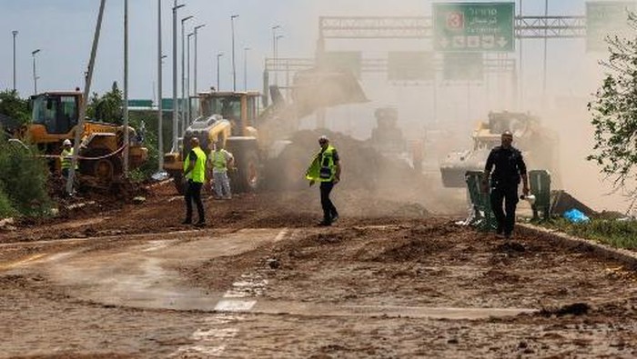 Members of Israeli security services inspect a crater near a road outside Israels Ben Gurion airport after a missile launched from Yemen struck the area on May 4, 2025. A missile launched from Yemen struck near Israels main international airport on May 4, Israeli authorities said, an attack that briefly halted air traffic and triggered threats of retaliation. (Photo by Jack GUEZ / AFP)