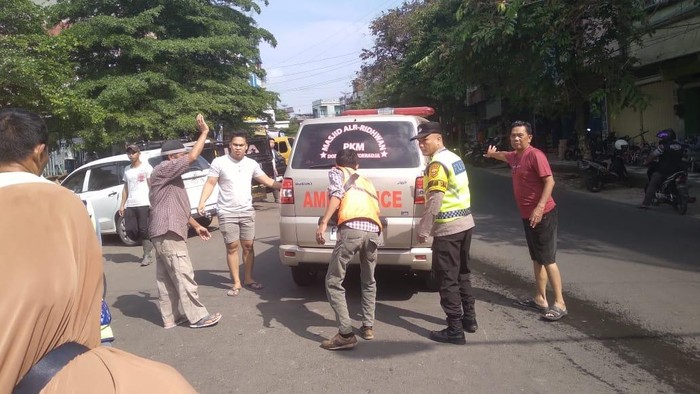 Polisi bersama warga saat mengevakuasi jenazah tukang ojek yang meninggal saat menunggu penumpang