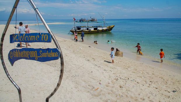 Wisatawan bermain air di tepi pantai Pulau Gili Ketapang, Kabupaten Probolinggo, Jawa Timur, Minggu (4/5/2025). Pulau dengan luas sekitar 68 hektare yang termasuk Kawasan Konservasi Perairan Daerah (KKPD) dengan kategori taman wisata perairan tersebut menawarkan panorama pasir putih serta sejumlah fasilitas paket wisata seperti transportasi, alat selam, wahana banana boat, hingga sajian kuliner ikan laut. ANTARA FOTO/Irfan Sumanjaya/tom.