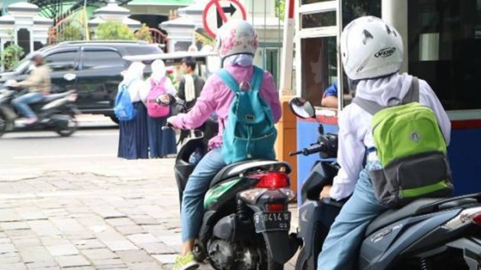 Anak SMA naik motor.