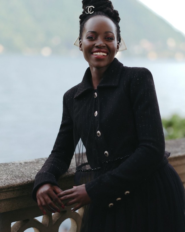 Aktris Lupita Nyong’o tampil chic sekaligus elegan dengan setelan serba hitam, berupa jaket tweed yang ikonik serta rok tulle transparan. Bintang film ‘Black Panther’ ini melengkapi busananya dengan kacamata hitam dan headpiece berlogo CC di rambut. Foto: Instagram/@chanel