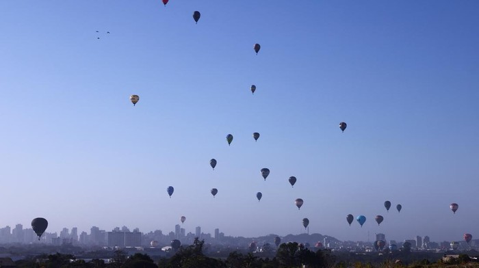 A balloonist flies next to a paraglider during a competition at the 35th Balloon Festival in Torres, Rio Grande do Sul, Brazil, May 3, 2025. REUTERS/Diego Vara