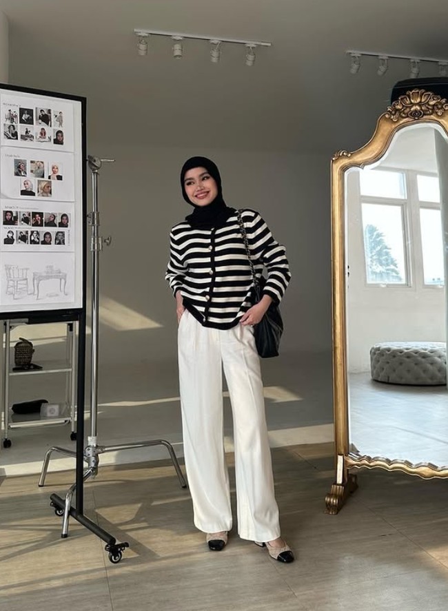 Fira Assegaf atau akrab disapa Sashfir, merupakan salah satu influencer hijab yang mempopulerkan gaya hijab meleyot. Ia sengaja menata hijab yang terlihat tidak tegak di atas dahi. Ia memadukan hijab dengan cardigan knit dengan celana putih. Foto: Dok. Instagram @sashfir.