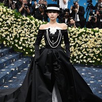 Gaun hitam dengan garis leher off-shoulder apik berpadu bersama celana pensil di bawahnya. Ekor bervolume menyentuh lantai membuat penampilan Jennie kali ini lebih dramatis. Foto: Kevin Mazur/Getty Images for The/Kevin Mazur/MG25