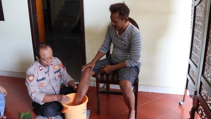 Kepala SPKT 1 Polsek Jakenan, Polres Pati, Aiptu Pudiyanto, saat mengobati warga yang terkena gigitan ular dengan pengobatan alternatif. Foto diunggah Selasa (6/5/2025).