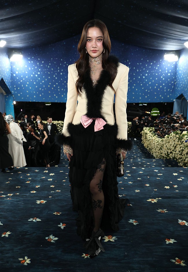 Penampilan aktris Thailand, Freen Sarocha tak kalah mencuri perhatian saat tiba di blue carpet Met Gala 2025. Brand ambassador terbaru Valentino itu mengenakan blazer berwarna nude, yang berhias bulu dan aksen pita. Di balik rok hitam yang menjuntai, dia memakai stocking bermotif floral. Foto: Getty Images